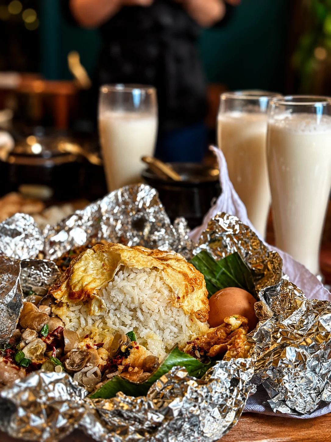 Foil-wrapped rice meal with eggs, vegetables and drinks